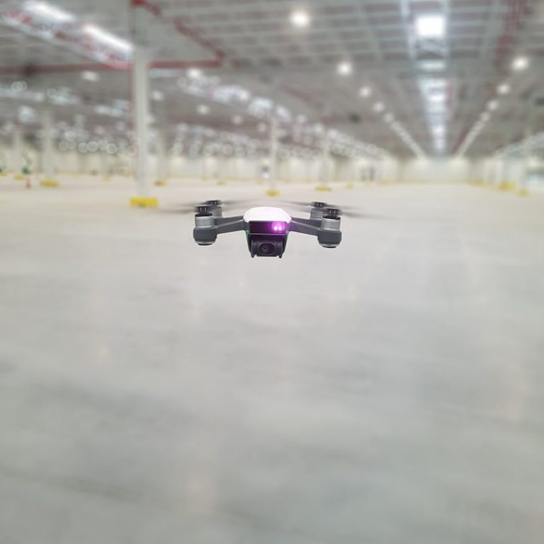 Eine Drohne schwebt in einer großen, leeren Lagerhalle.