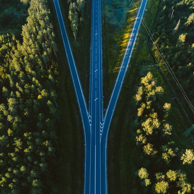 Luftaufnahme einer Straßenkreuzung mit separierten Fahrspuren und umgebenden Bäumen.